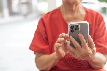 Hands focus with copy space of grandmother who is using smartphone to connect to people shows concept of senior person using digital technology for communicating to retired person community.