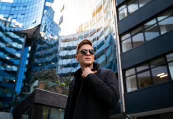 Fashionable man posing in tall modern buildings surroundings 