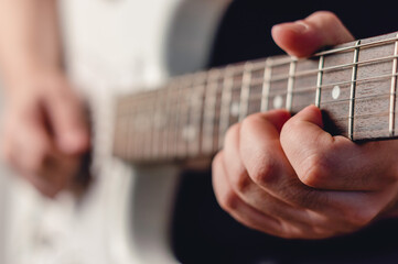 close-up male hand playing electric guitar making a chord, focus on left hand, copy space