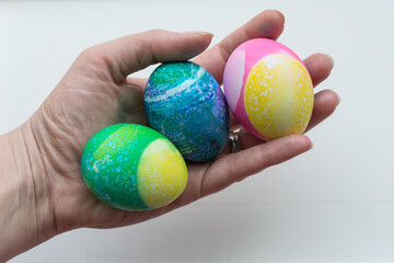Woman holds three dyed and decorated Easter eggs in her hand; recipes for hard boiled eggs; plain white background