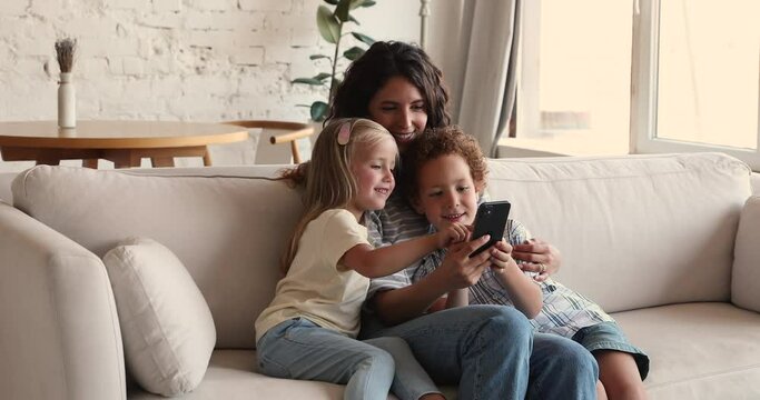 Single mom involve children school age son little daughter into education activity on phone show video help to answer question at online guessing game. Two diverse kids use cell under parental control