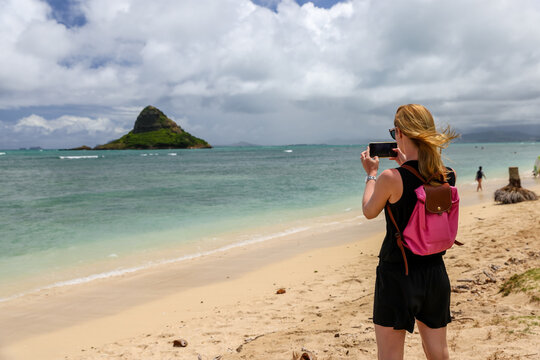 Young woman taking pictures of Mokoliʻi Island off the shores of Oahu