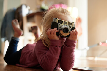 Can I have a smile. Shot of a little girl taking a picture with a camera.