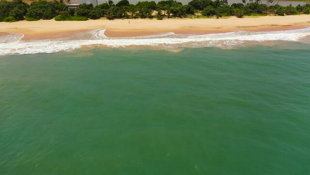 Beautiful sandy beach with palm trees and sea surf with waves. Lankavatara, Sri Lanka.