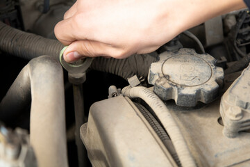 Obraz premium A man's hand holds on to the dipstick to check the oil level.