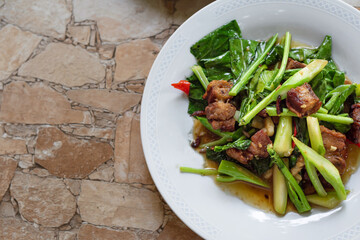 Stir fried kale vegetables with fried pork in the plate for breakfast or lunch or dinner,some menu on food table