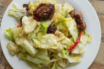 Stir fried collard greens with fried pork in the plate for breakfast or lunch or dinner,some menu on food table