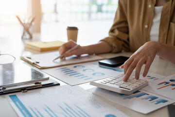Fototapeta premium Close up of business woman or accountant working on calculator to calculate business data, accountancy document and laptop computer at office, business concept