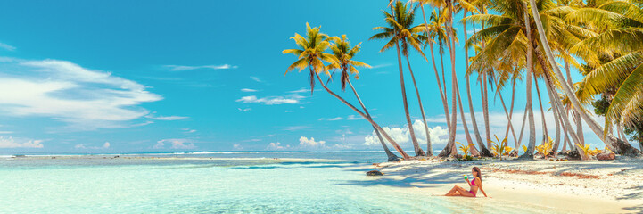 Beach suntan bikini woman sunbathing lying in ocean drinking tropical drink. Travel vacation...