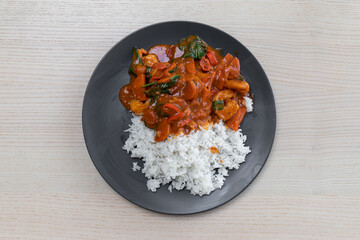A plate of red curry with steam rice.