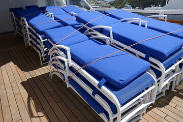 Lounge chairs with blue cushions stacked up on cruise ship wooden deck Lounge chairs with blue cushions stacked up on cruise ship wooden deck