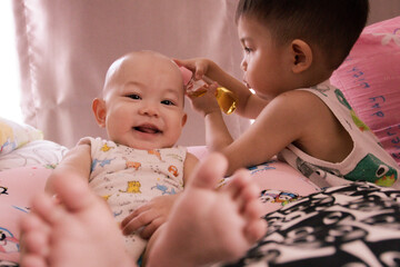 The Asian baby and her brother feel happy and playing well in living room. © sippakorn