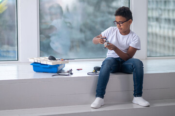 A dark-skinned boy constructing a transformer and looking busy