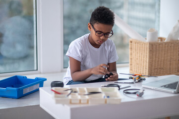 A dark-skinned boy constructing a transformer and looking busy