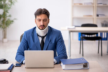 Young neck injured male employee sitting in the office