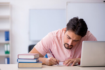 Young male student preparing for exams in the classroom