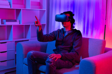 Fototapeta premium Man wearing virtual reality glasses is playing a 3D game with excitement, Bluetooth Remote Controller, VR, Future games, Gadgets, Technology, Red and blue background, VR game concept.