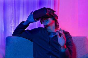 Man wearing virtual reality glasses is playing a 3D game with excitement, Bluetooth Remote Controller, VR, Future games, Gadgets, Technology, Red and blue background, VR game concept.