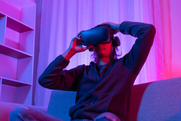 Man wearing virtual reality glasses is playing a 3D game with excitement, Bluetooth Remote Controller, VR, Future games, Gadgets, Technology, Red and blue background, VR game concept.