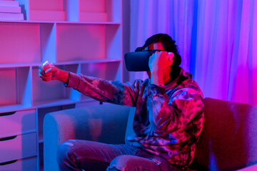 Man wears virtual reality glasses and uses joystick to play games with fun, VR, Future games, Technology, Red and blue background, Touch Controller, Bluetooth Remote Controller, VR game concept.