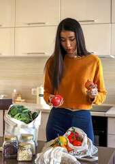 Young Asian woman takes out red apples from a grocery bag. Reusable package. Zero waste.