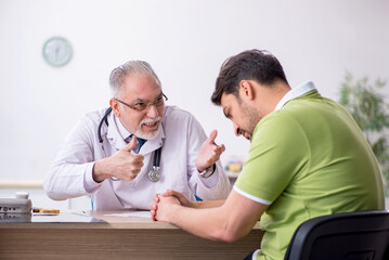 Young man visiting old male doctor