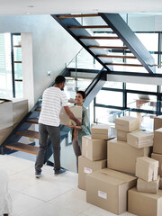 They make moving house look easy. Shot of a happy young couple passing boxes to each other while...