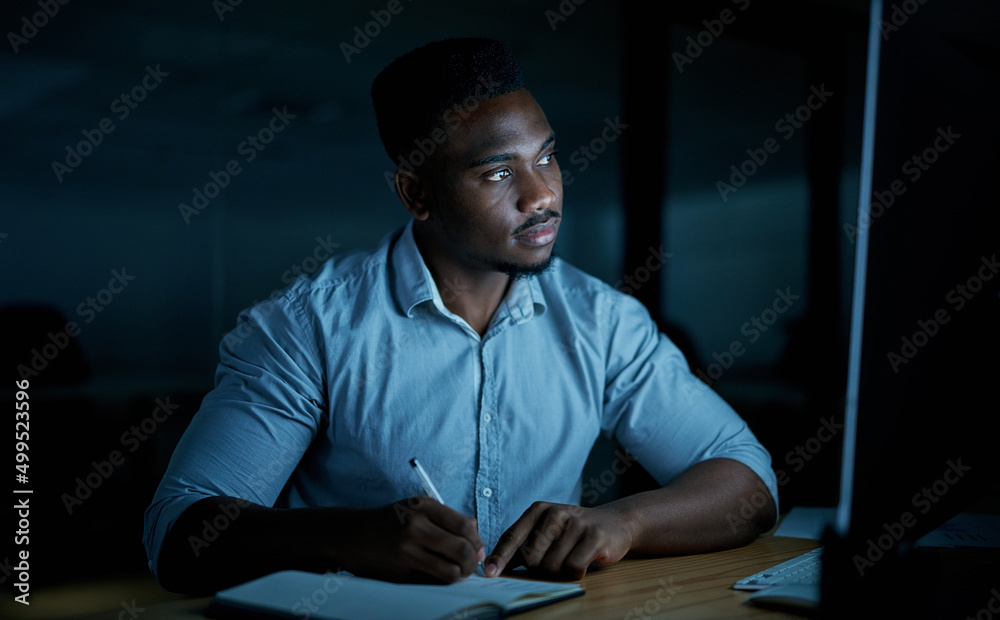 Aufkleber You cant finish a task without a bit of focus. Shot of a young businessman writing in a notebook and using a computer during a late night at work.