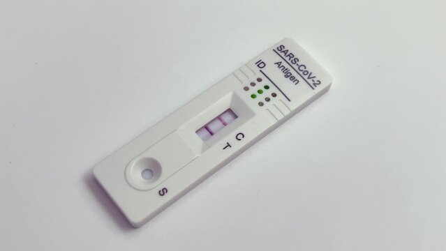 Performing COVID-19 antigen flow test. The test indicates a positive result. Wide framing.