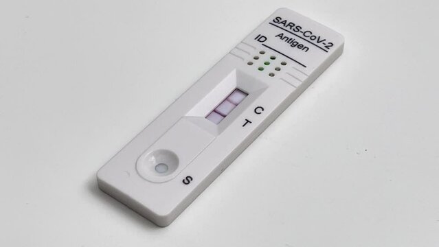 Performing COVID-19 antigen flow test. The test indicates a positive result. Tight framing.