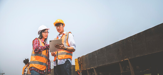 Team engineers are on duty and discussed by using tablet in the job site of train garage.