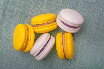 Sweet and bright banana macarons with chocolate filling on a green background. French dessert.