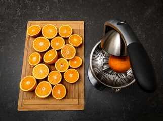 Orange juicer with sliced oranges on a cutting board