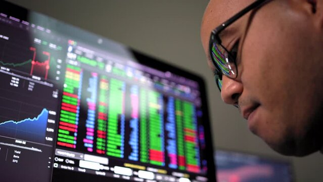 Investor businessman analyzing a graphic of a stock, cryptocurrency exchange chart and looks at computer monitor. Financial analyst working with real-time exchange rate diagram. Investment concept.