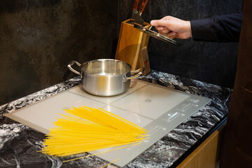 Close-up. A man cooks spaghetti in the kitchen. He dips the pasta into a pot of boiling water.