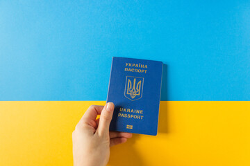 Woman's hand hold Ukraine biometric passport on the national flag of Ukraine. Blue and yellow...