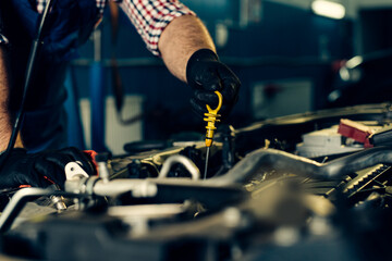 Fototapeta na wymiar Car mechanic checking oil level in a mechanical workshop