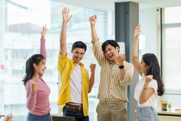 Successful group of young Asian business people achieving goals excited raised hands rejoicing. New startup project concept.