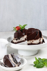 Puding Oreo. Black cookies pudding on white plate with a cup of sauce.