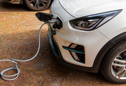 Electric car with charging station in the process of charging - Powered by Adobe