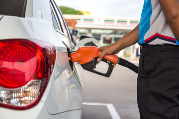 Transportation and ownership concept - man pumping gasoline fuel in car at gas station. hight price...