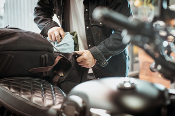 rider take the clothes out of the side bag or saddlebags of motorcycle after trip ,motorcycle travel concept. selective focus