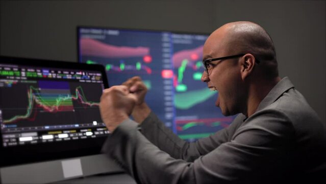 Investor victory moment analyzing a graphic of a stock, cryptocurrency exchange chart and looks at computer monitor. Financial analyst working with real-time exchange rate diagram. Investment concept.