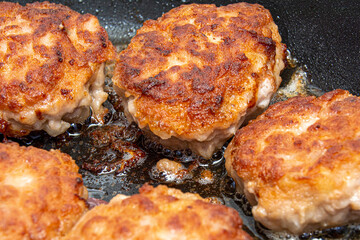 Meat burgers or cutlet-shaped patty being shallow fried in oil on a frying pan, close up. Russian kotlety