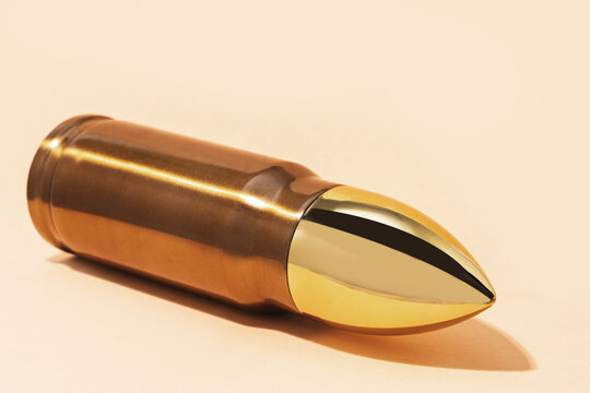 Big and shiny bullet against beige background