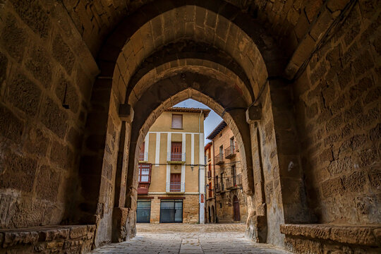 Rustic medieval stone archway in a street in Olite, Spain famous for a magnificent Royal Palace castle on a rainy day with puddles on cobblestones