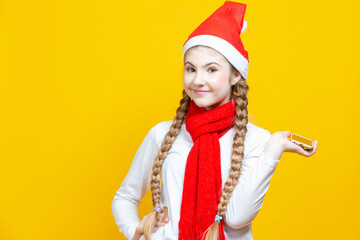 Positive Winsome Caucasian Girl With Cellphone For Taking Selfie While Wearing New Year Christmas Santa Hat And Posing Against Yellow Background.