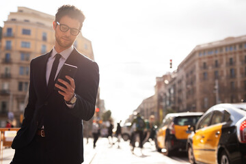 Handsome businessman using the phone. Young elegance man outdoors..