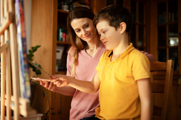 Mother and son painting at home. Little boy drawing with mom in living room.