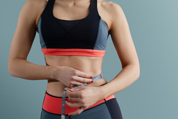 Weight loss, slim body, healthy lifestyle concept. Fit fitness girl measuring her waistline with...